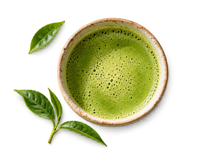 Schale mit grünem Matcha und frischen Teeblättern